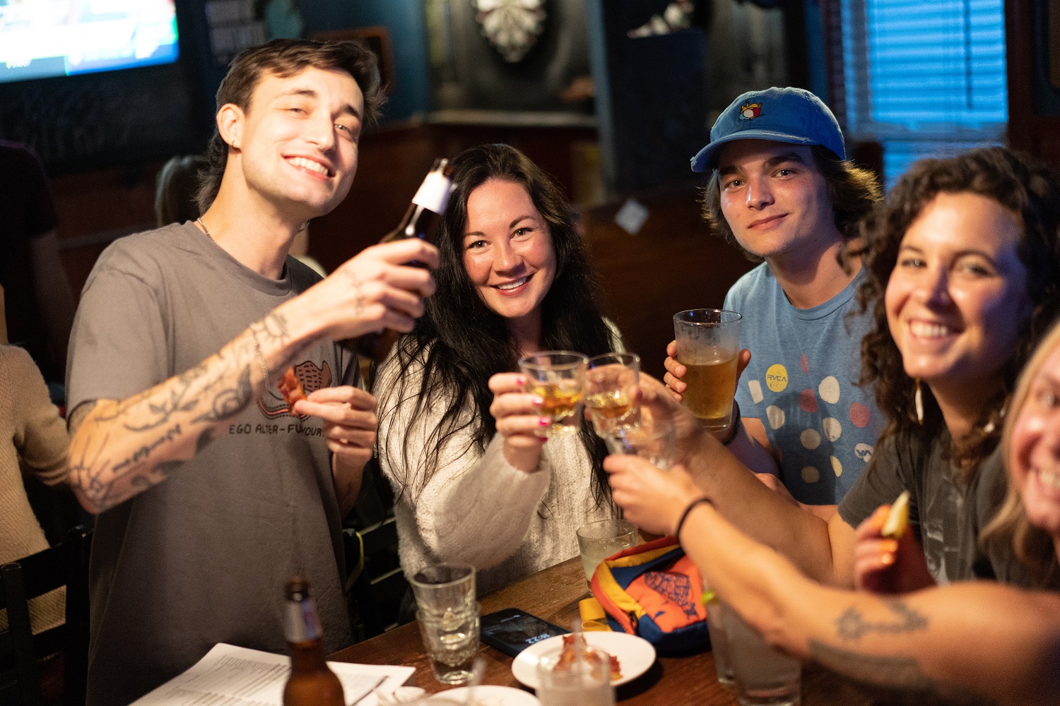 Friends cheers-ing pint glasses together at Logan's Alley bar